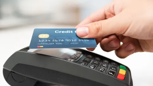 Photo of a person using their credit card on a credit card reader