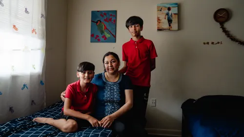 Photo of a woman and two boys in a bedroom with two beds.