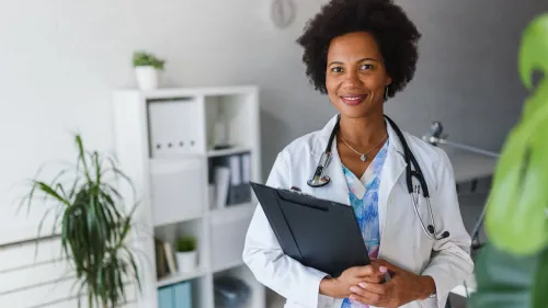 A female doctor with a stethoscope around her neck and holding a clipboard