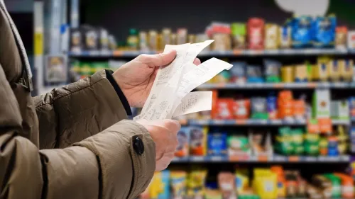 A person in a grocery store holding several receipts