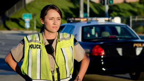 A police officer standing in the road next to a police car
