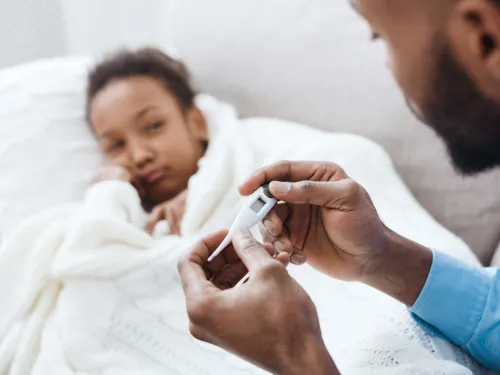 Photo of a father reading a thermometer to check if his daughter has a fever.