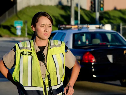 A police officer standing in the road next to a police car