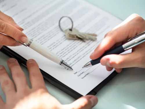 Fotografía de una persona firmando un contrato de arrendamiento de una propiedad.