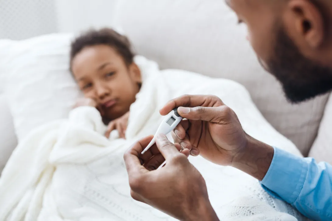Photo of a father reading a thermometer to check if his daughter has a fever.